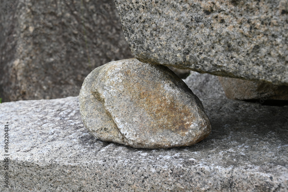 A small stone between two large stones. A little stone supporting other stones. A small stone between two large stones. A little stone supporting other stones.
