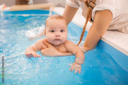 Litle baby in pool swimming bathing during health procedures.