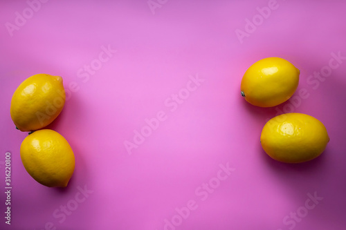 Flat lay composition with yellow lemons and space for text on color pink background.