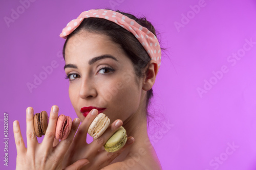 bellissima ragazza anni 50 tiene in mano dei macarons - isoplata su sfondo rosa