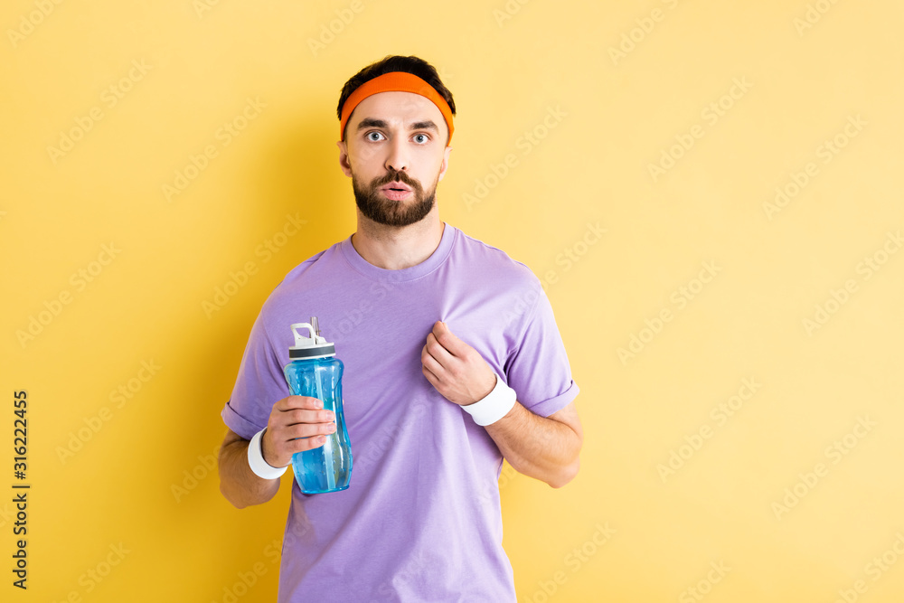 tired sportsman holding sports bottle on yellow