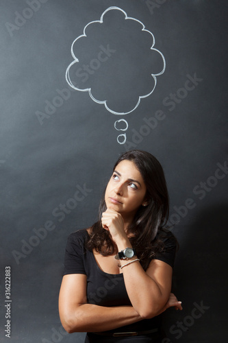ragazza isolata su sfondo nero ha una nuvoletta da fumetto sopra la testa e guarda verso l'alto pensierosa photo