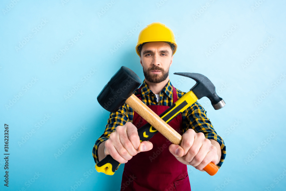 selective focus of workman holding hammers on blue selective focus of workman holding hammers on blue