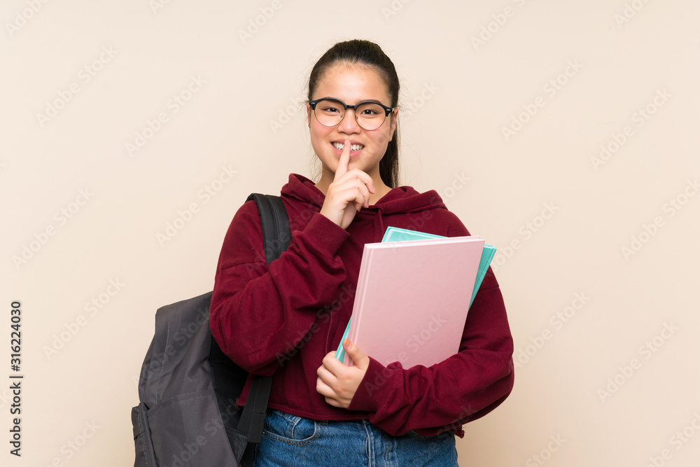 Fototapeta premium Young student Asian girl woman over isolated background doing silence gesture