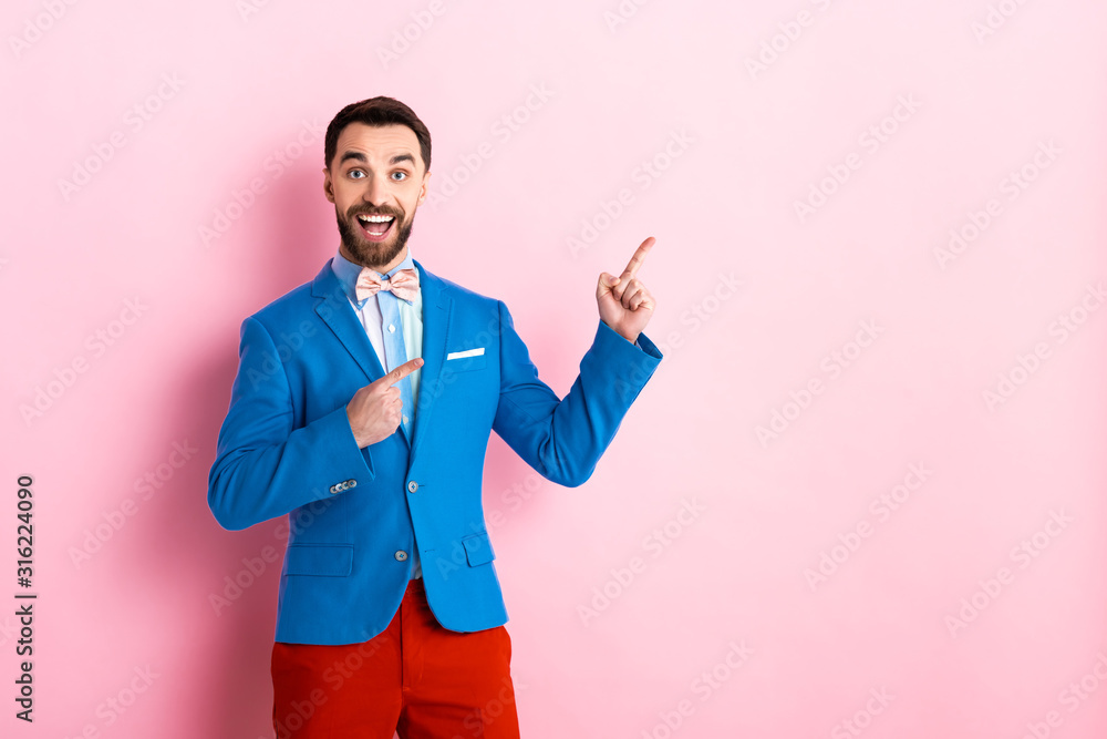 excited man in suit pointing with fingers on pink