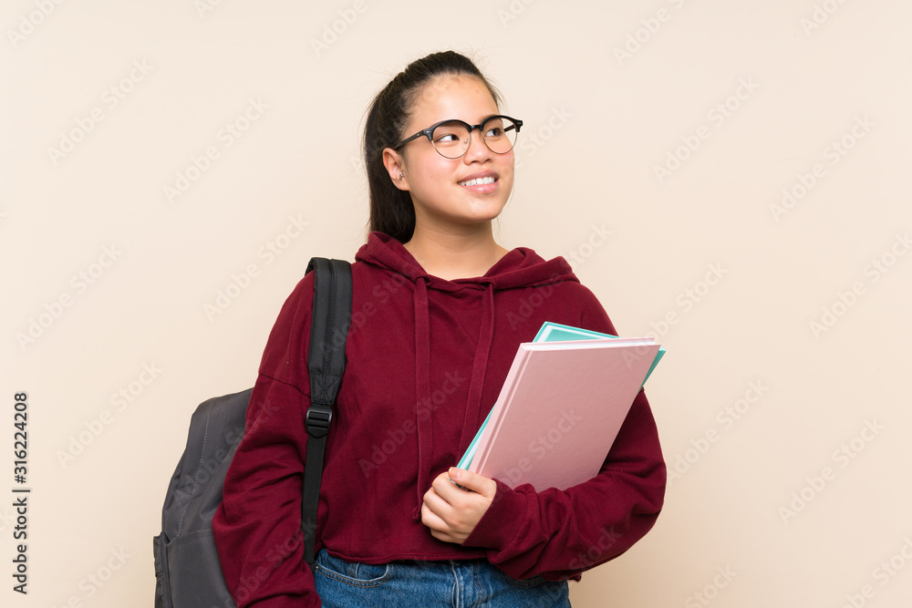 Fototapeta premium Young student Asian girl woman over isolated background laughing and looking up