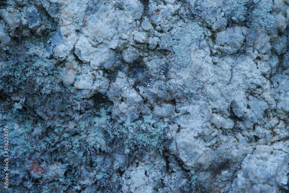 Fototapeta premium A closeup photo of bedrock, coloured light blue by quartz and light green by lichens