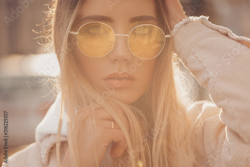 Beautiful stylish blonde woman in yellow sunglasses in outdoor.