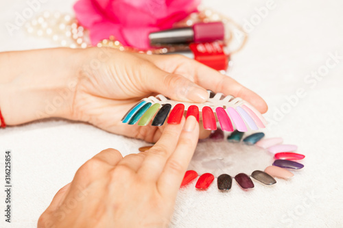 Hands of a woman who chooses the color of her nail polish