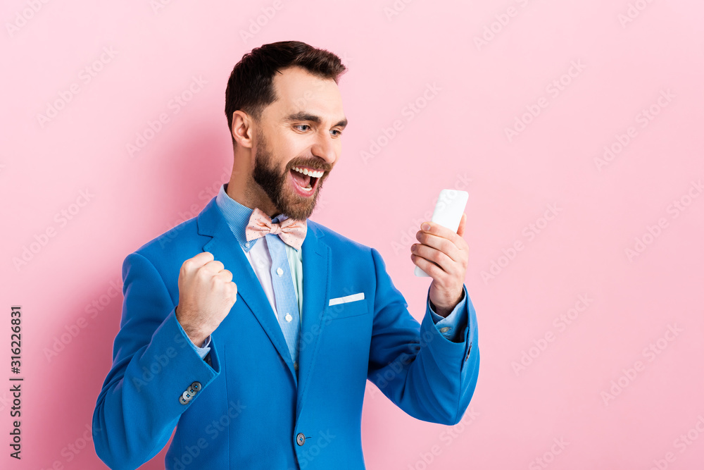 excited bearded businessman holding smartphone on pink excited bearded businessman holding smartphone on pink