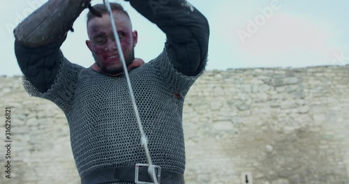 Strong warrior with malice killing enemy with sword at camera