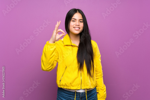 Young teenager Asian girl over isolated purple background showing ok sign with fingers