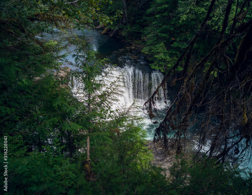 Impressive Taitnapum falls with a large watershed in the Gifford Pinchot National Forest surrounded by trees and branches on the Lewis River Skamania county in the summertime. Impressive Taitnapum falls with a large watershed in the Gifford Pinchot National Forest surrounded by trees and branches on the Lewis River Skamania county in the summertime.