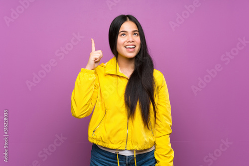Young teenager Asian girl over isolated purple background intending to realizes the solution while lifting a finger up