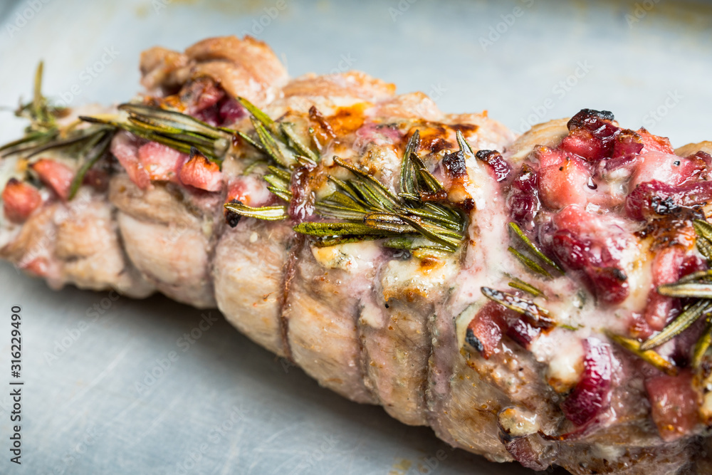 Baked pork loin with fruits, blue cheese and rosemary. Selective focus. Shallow depth of field.