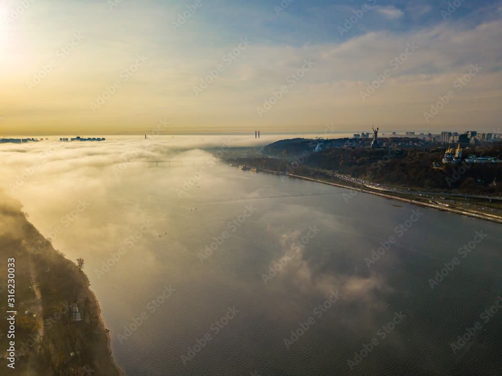 Aerial drone view. Light fog rises from the Dnieper River and covers Kiev.