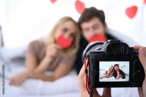 Beautiful couple smiling and enjoying / Young couple taking selfie with digital camera in their bedroom.