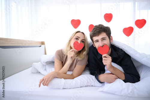 Couple. Love. Valentine's day. Man and woman are holding red paper hearts and kiss it.