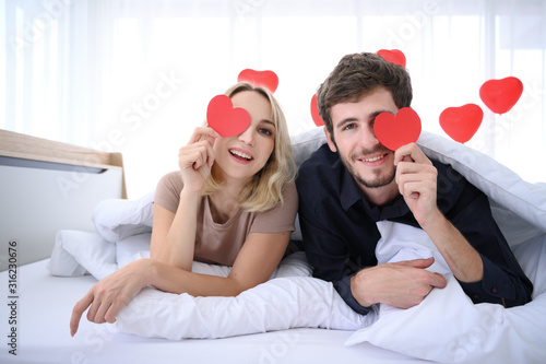 Couple. Love. Valentine's day. Man and woman are holding red paper hearts and smiling