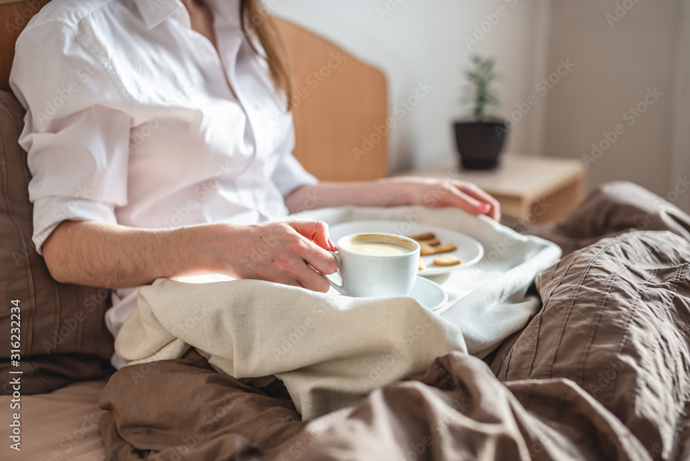 Woman have a romantic Breakfast in cozy morning bed. Coffee and word love from cookies. Surprise on Valentine's day