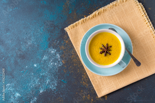 Fotografie Ayurvedic golden turmeric latte milk  tea made with turmeric and other spiceson blue background