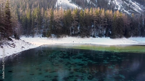 Aerial flyby over winter landscape of Gruner See, famous green lake in Tragoss, Styria, Austria. Travel destination. Look at mountains and forests surrounding the frozen lake. photo