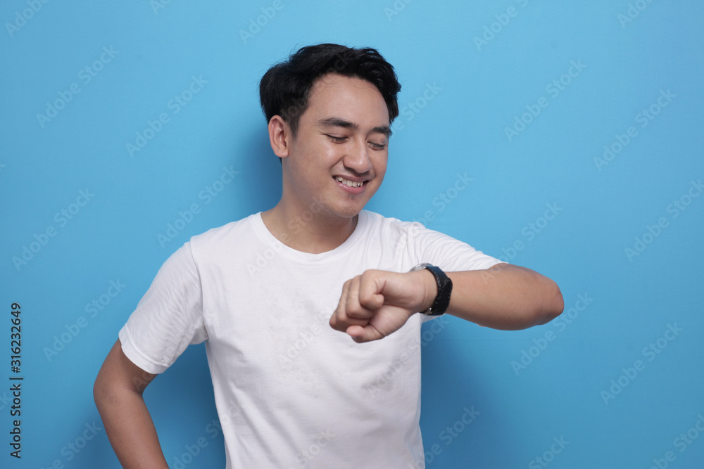 Young Asian male student checking time on wrist watch and smile Young Asian male student checking time on wrist watch and smile