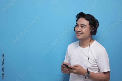 Fotografie Young Asian man listening to music on his smart phone