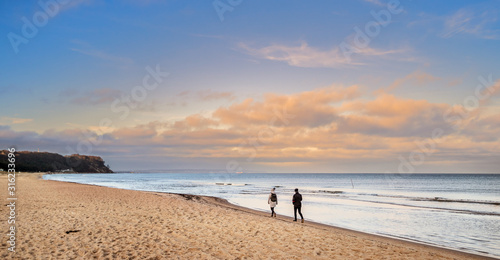 Frau und Mann spazieren am Meer, Ostsee vor orangen Wolken