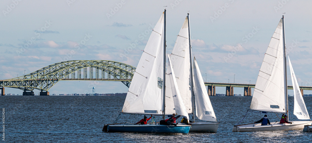 Three two person sailboats with The Great South Bay Bridge in December Three two person sailboats with The Great South Bay Bridge in December