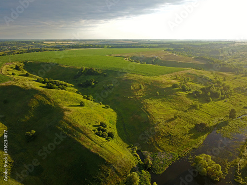 Aerial drone view. Green hills among meadows in the sunset