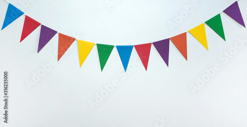 The concept of the birthday in the style of minimalism. A garland of triangular multicolored paper flags on a white background. Free space.
