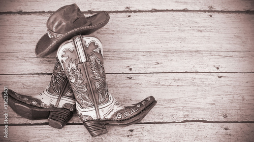 cowboy boots and hat on a wood background with vintage tinted effect and writing space