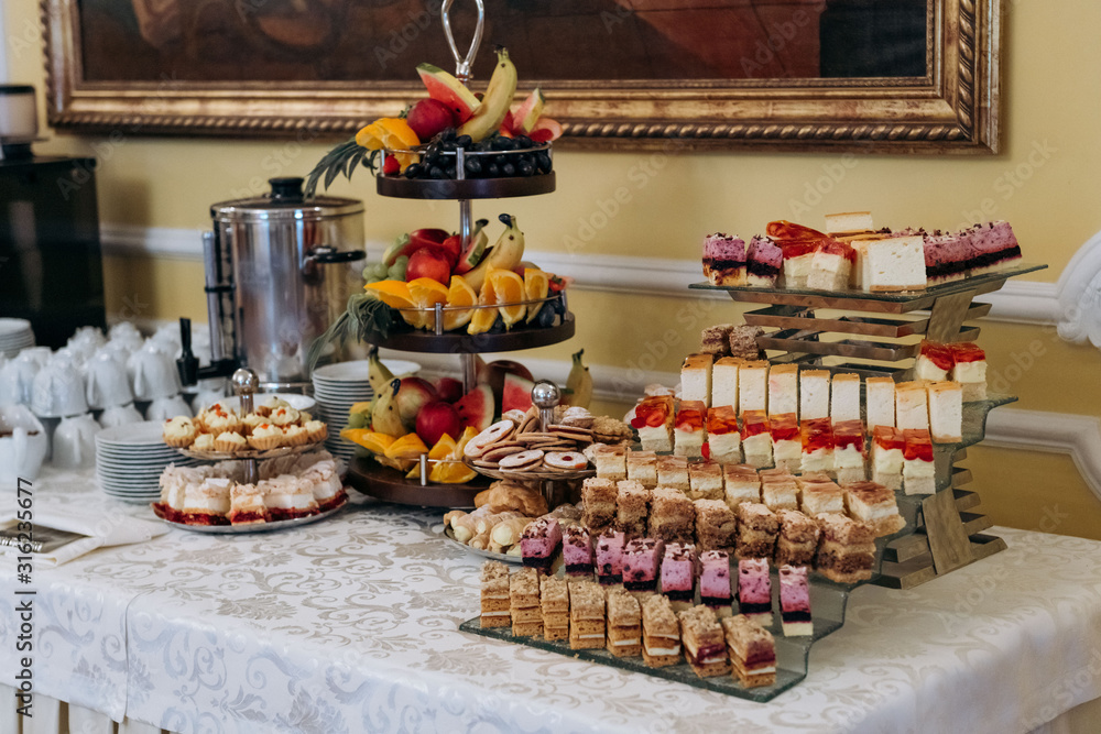 Table with sweet cakes, fruit and coffee machine at the wedding