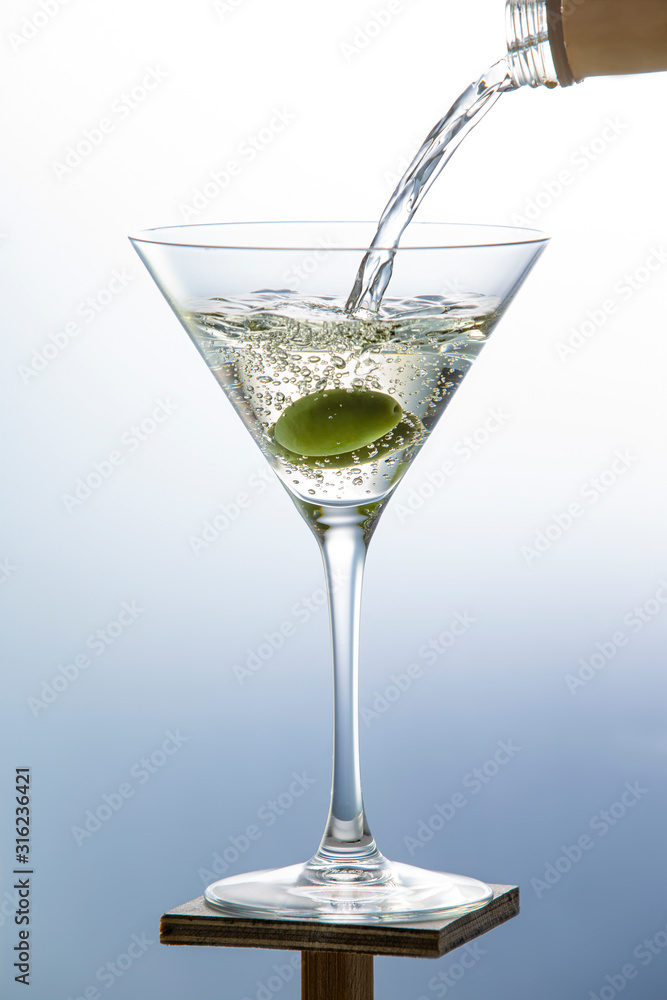 White wine pouring from a bottle into a glass with olives