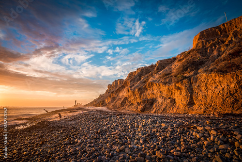 Beautiful beach sunset with sunlit bluffs and a rocky shore