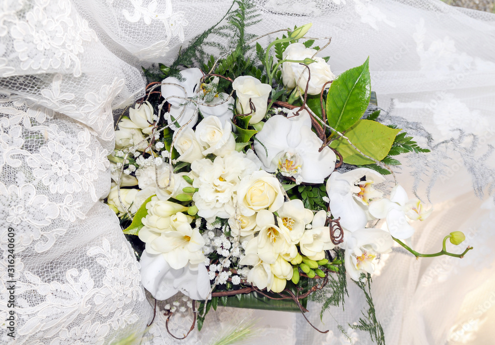 Ramo con rosas, lirios y orquídeas blancas y hojas verdes sobre el vestido  de una novia Stock Photo | Adobe Stock