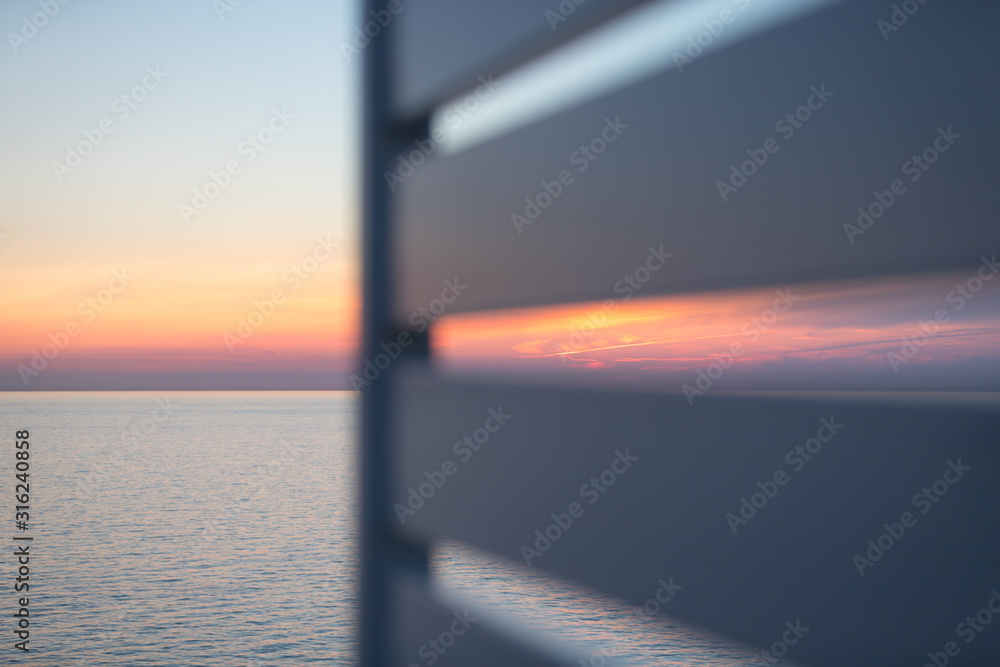Fototapeta premium Blick auf den Sonnenuntergang am Horizont vom Deck eines Schiffes aus