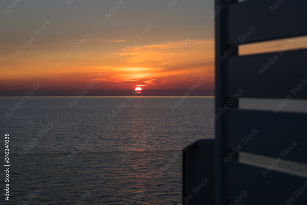 Fototapeta premium Blick auf den Sonnenuntergang am Horizont vom Deck eines Schiffes aus