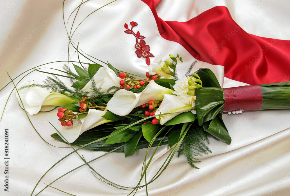 Ramo de flores de alcatraz blanco sobre vestido de novia con adornos rojos  foto de Stock | Adobe Stock