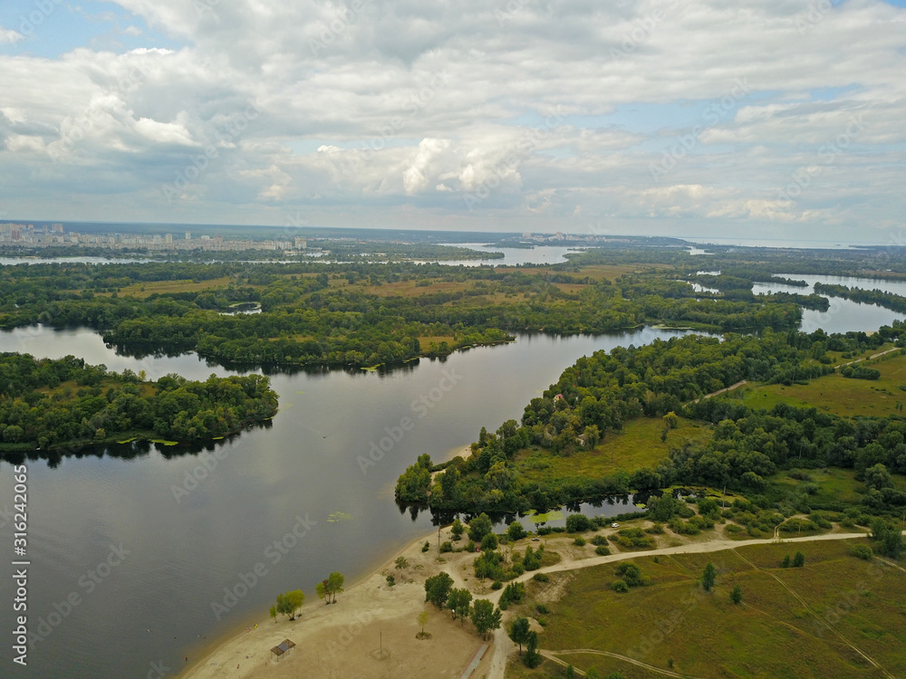 Aeiral drone view. Green banks of the Dnieper River near Kiev in cloudy weather on the outskirts of the city.