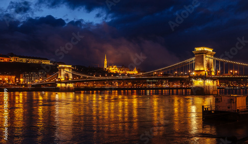 Night View Of Szechenyi Bridge. Famous Chain Bridge Of Budapest. Beautiful lighting and reflection in the Danube River.