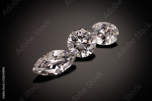 A marque, round and oval cut diamonds sit on a black sandblasted glass reflective background.