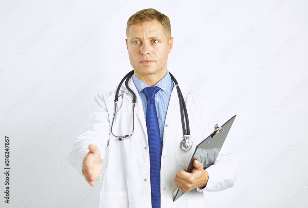 Young doctor in white coat with a stethoscope greets holding out his hand Young doctor in white coat with a stethoscope greets holding out his hand