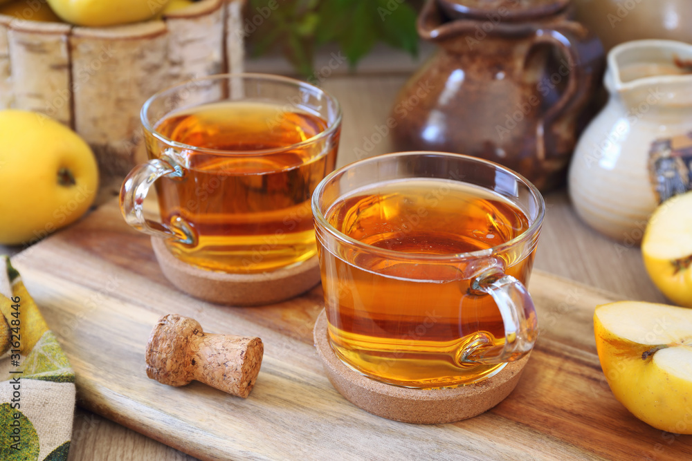 Two cups of Apple Cider and yellow apples Two cups of Apple Cider and yellow apples