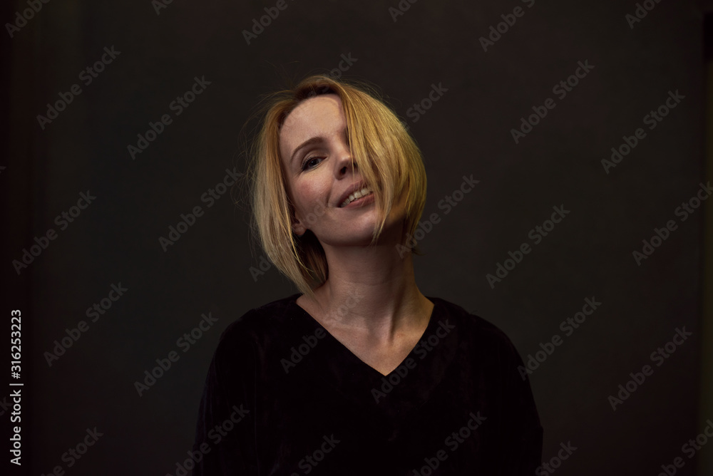 Fototapeta premium Woman is smiling on a dark background.