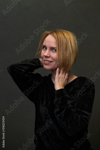 Woman is smiling on a dark background.