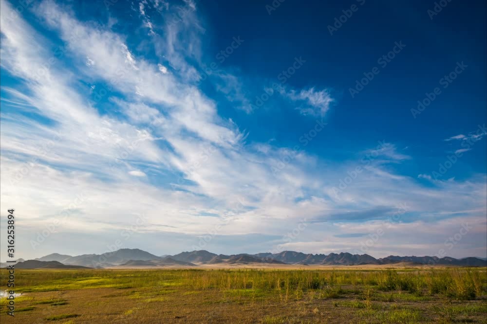 time lapse of white fluffy clouds in blue sky over plain at root of mountains time lapse of white fluffy clouds in blue sky over plain at root of mountains
