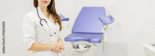 Professional medical physician gynecologist doctor in white uniform in clinic hospital. Gynecological cabinet with chair and other medical equipment on background. Woman health and pregnancy concept photo
