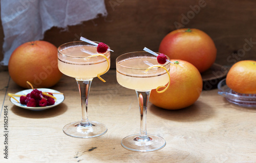 Champagne cocktail with grapefruit juice, garnished with zest and raspberries. Rustic style.